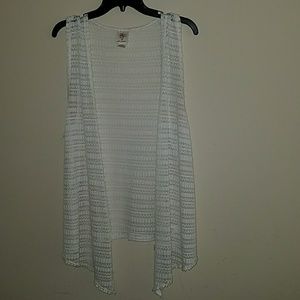 This is a white and laced sleeveless cardigan.